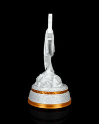 Side view of a white speckled draped cross statue on a tiered base with gold-tone trim.