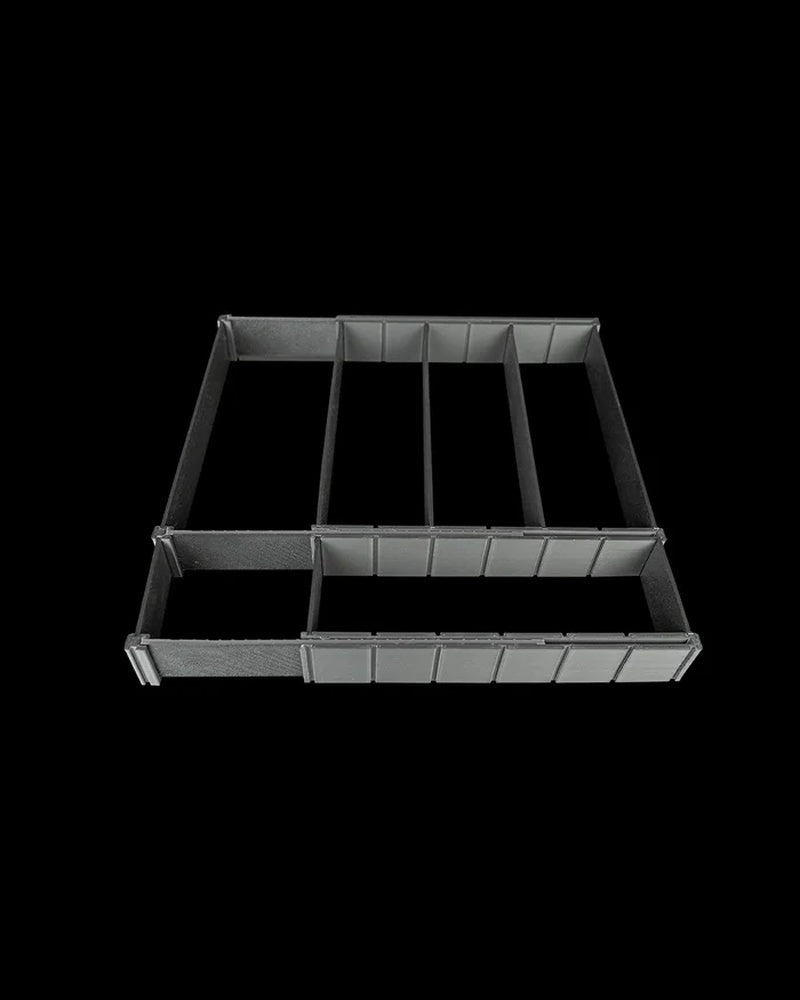Black partitioned drawer organizer with long open compartments on a dark background