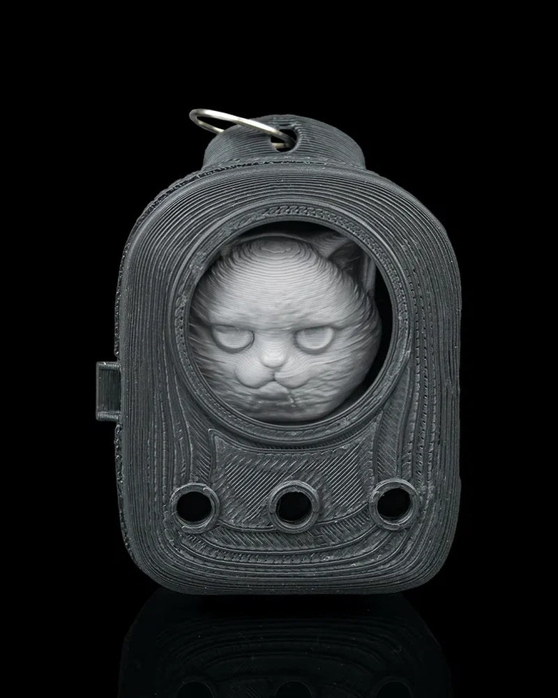 Grey cat face inside a dark backpack-shaped frame with a metal ring at the top