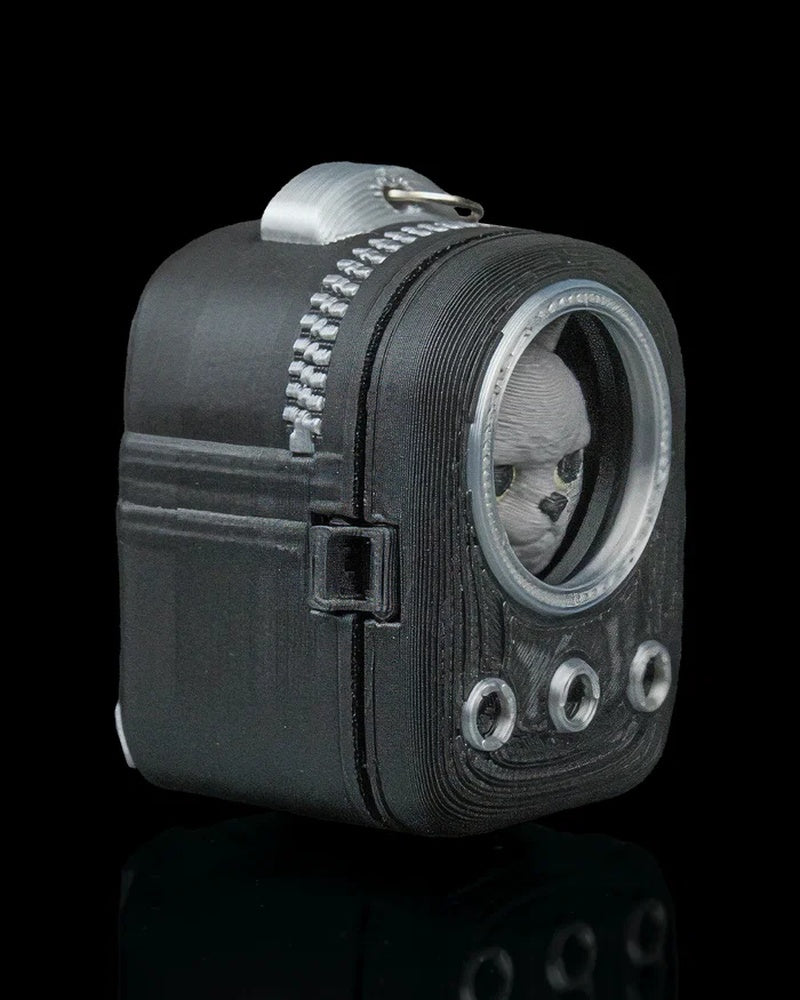 Angled side view of a dark backpack-shaped cat figure with a round front window and top ring