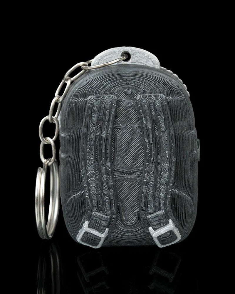 Back view of a dark backpack-shaped figure with strap details and a metal ring and chain