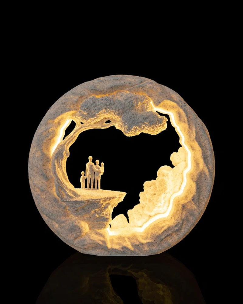 Round illuminated table lamp with a family group under a tree inside an open circular scene