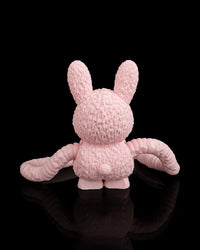 Back view of a pink monster figurine with tall ears and long arms on a black background