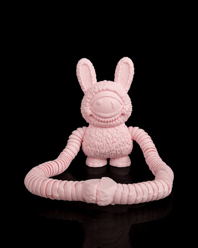 Front view of a pink monster figurine with a single unpainted eye and long arms on a black background