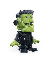 Angled front view of a green monster figurine with black spiky hair, black outfit, and white patches on its face and jacket.