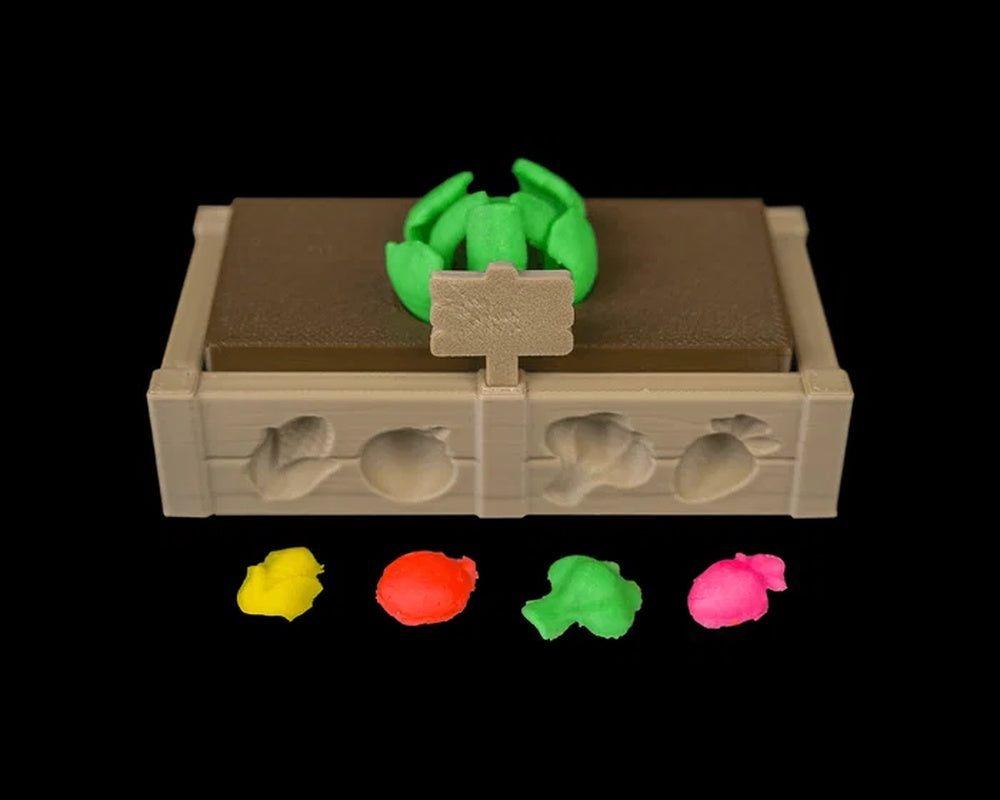 Tan garden bed tray with raised vegetable shapes, small sign, green sprout shape, and four bright colored lumps in front.
