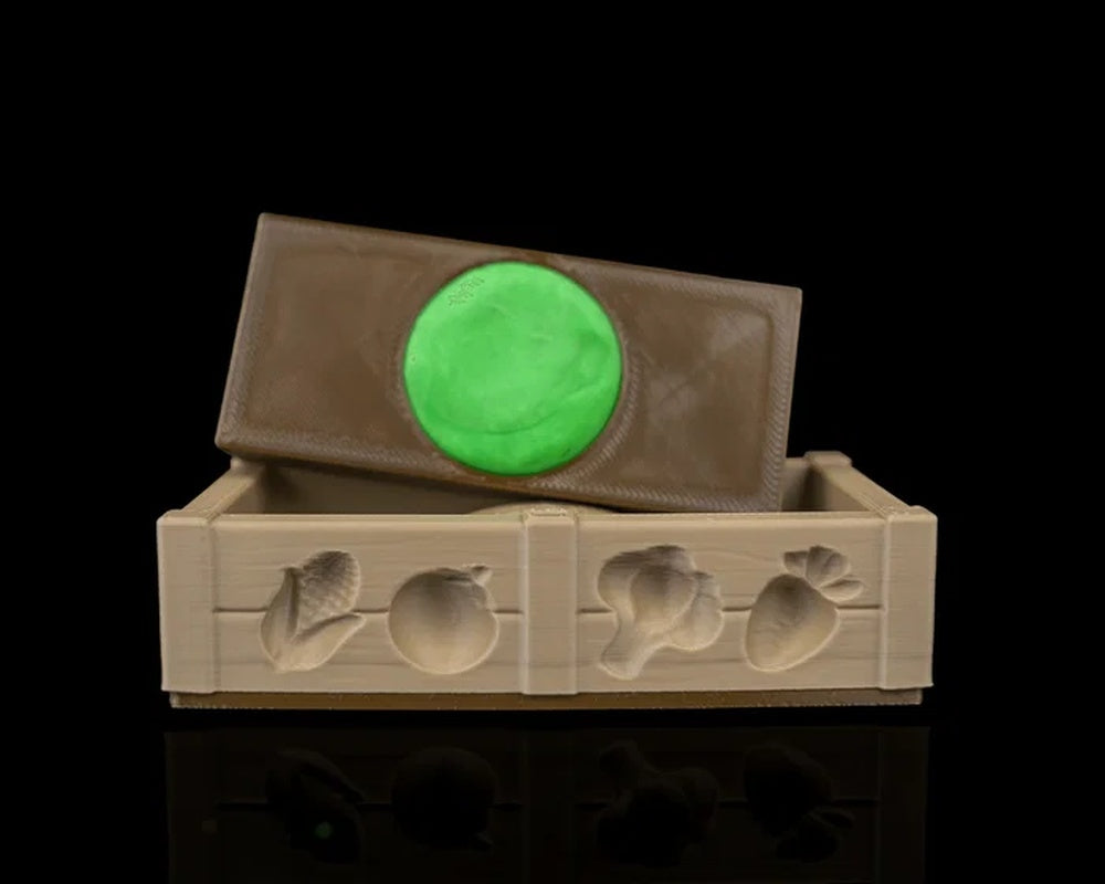 Brown rectangular insert tilted above a tan garden bed tray with a green round piece underneath.