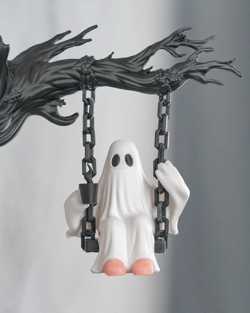 Front view of a white ghost figurine on a black swing with dark chain-like supports and a branch-like top