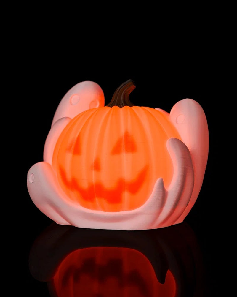 Glowing orange pumpkin lamp with white ghost shapes and a dark stem on a black background.