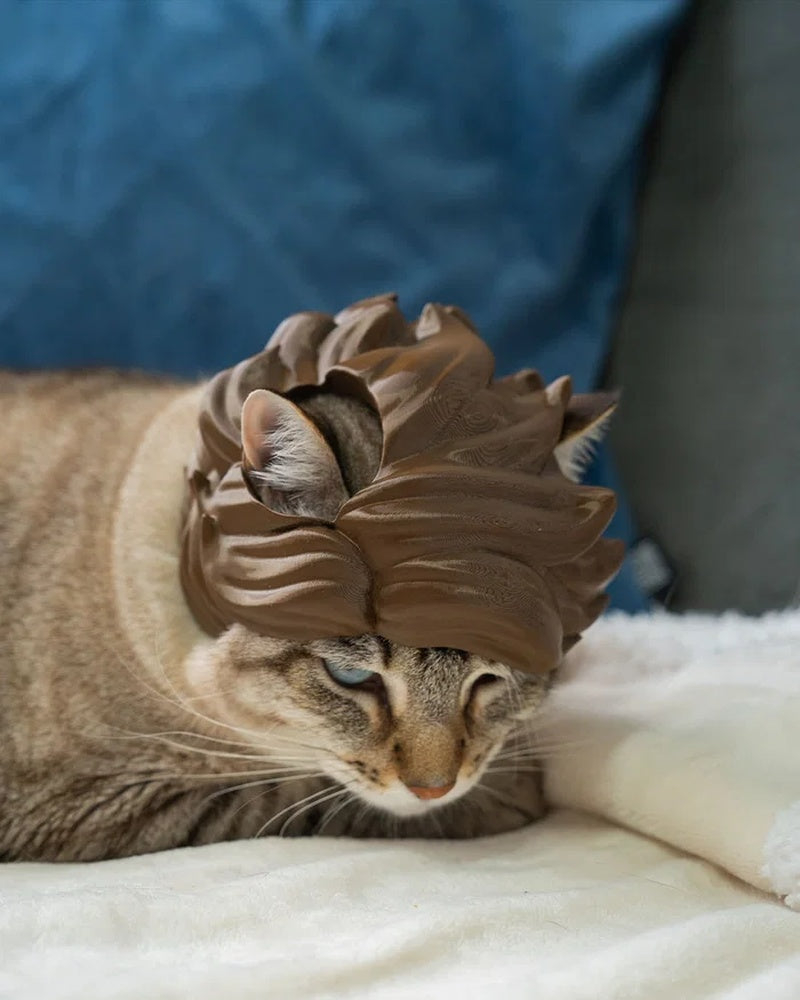 Tabby cat looking downward while wearing a brown wave-styled headpiece.