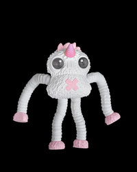White monster figurine with large dark eyes, a pink horn, pink feet and long ribbed arms on a black background