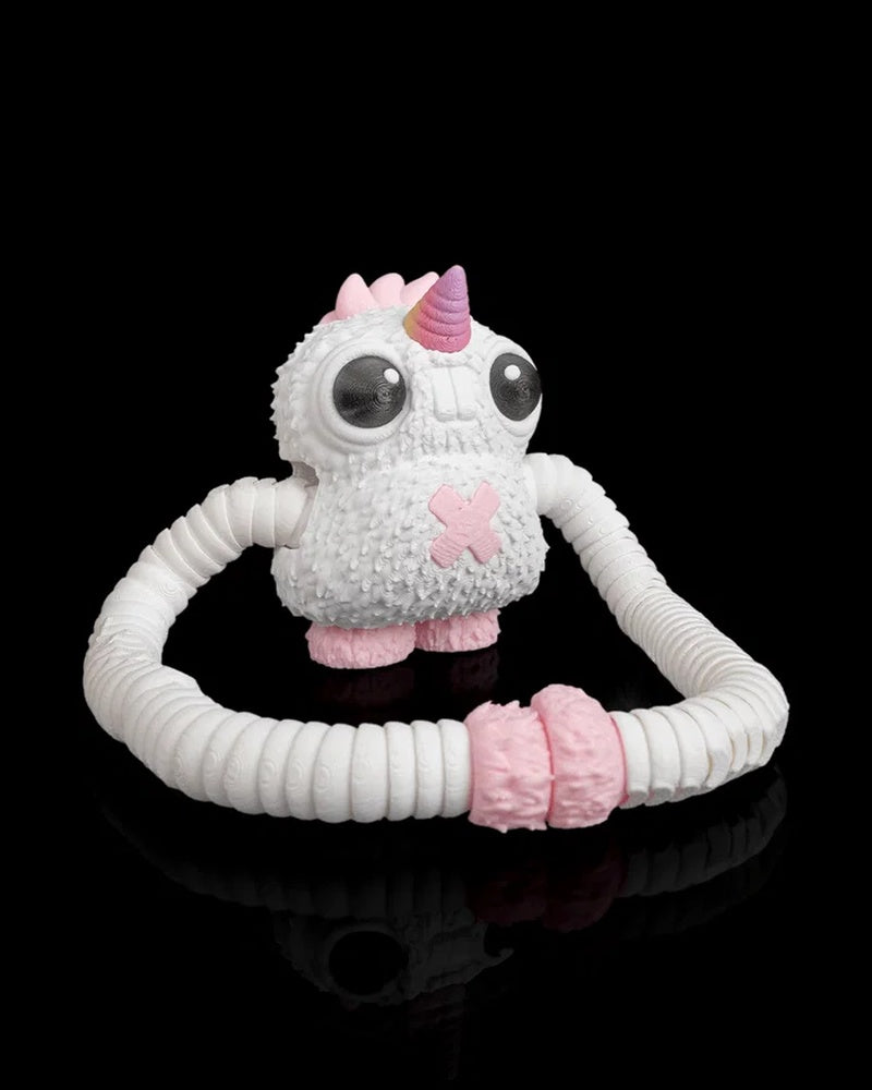 White monster figurine with a pink horn and long ribbed arms looped in front on a black background