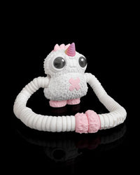 White monster figurine with a pink horn and long ribbed arms looped in front on a black background