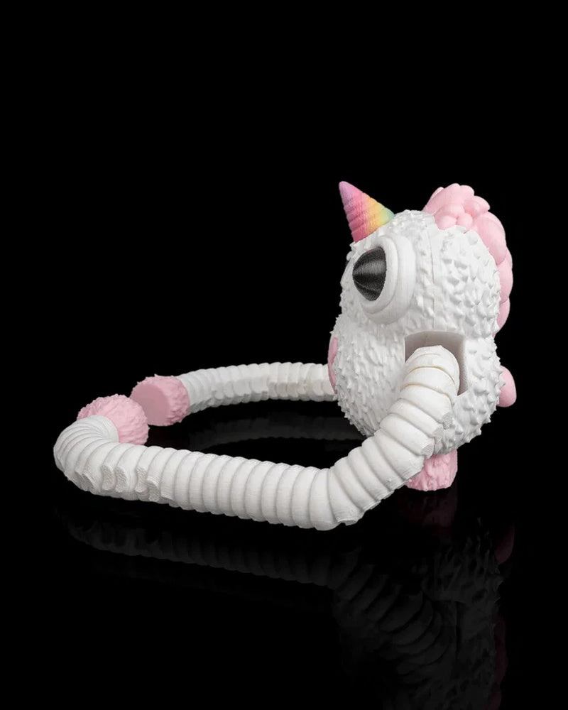 Side view of a white monster figurine with a pink horn, pink back spikes and long ribbed arms on a black background