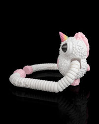 Side view of a white monster figurine with a pink horn, pink back spikes and long ribbed arms on a black background