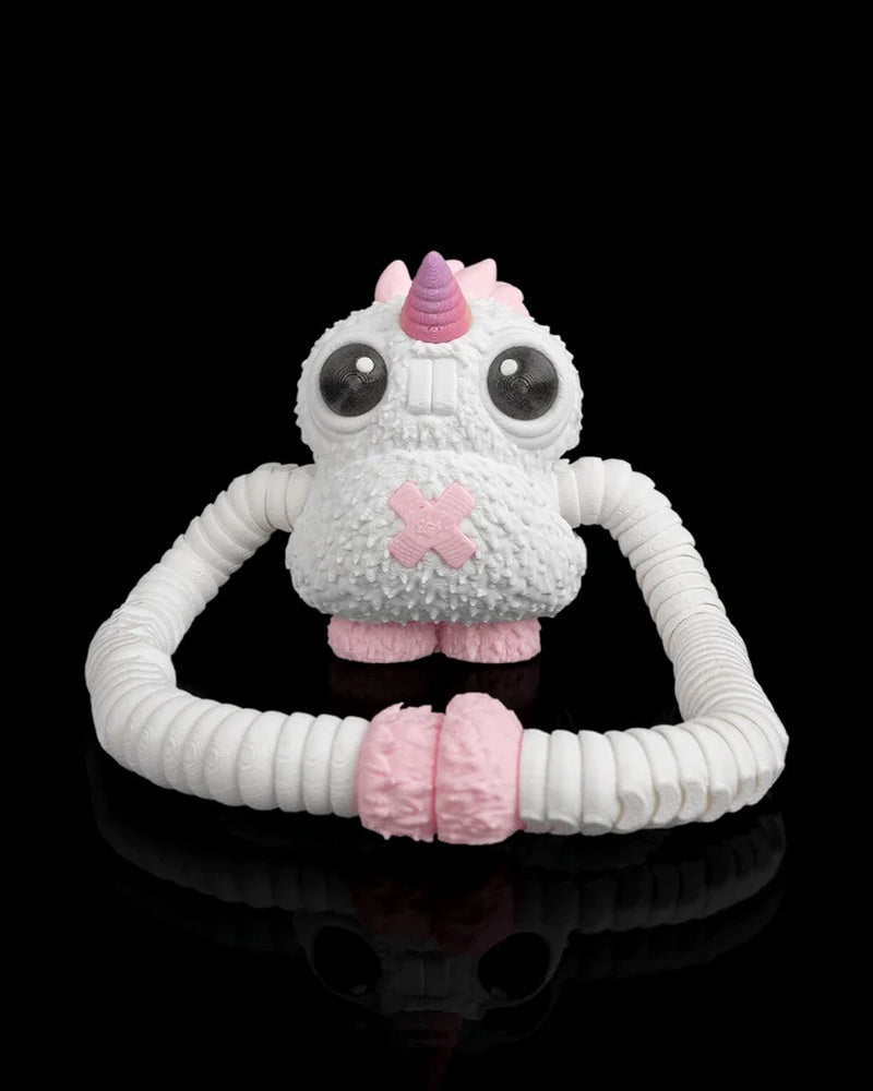 Front view of a white monster figurine with a pink horn, large dark eyes and looped ribbed arms on a black background