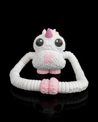 Front view of a white monster figurine with a pink horn, large dark eyes and looped ribbed arms on a black background