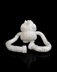 Unpainted white monster figurine with a horn, large eyes and ribbed arms on a black background