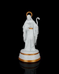 Front view of a white shepherd statue with gold halo, staff, and gold-accented round base against a black background.