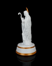 Side view of a white shepherd statue holding a curved staff on a gold-accented round base against a black background.