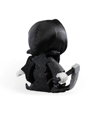 Rear angled view of a black hooded skull figure with white hands and a gray blade-like prop.