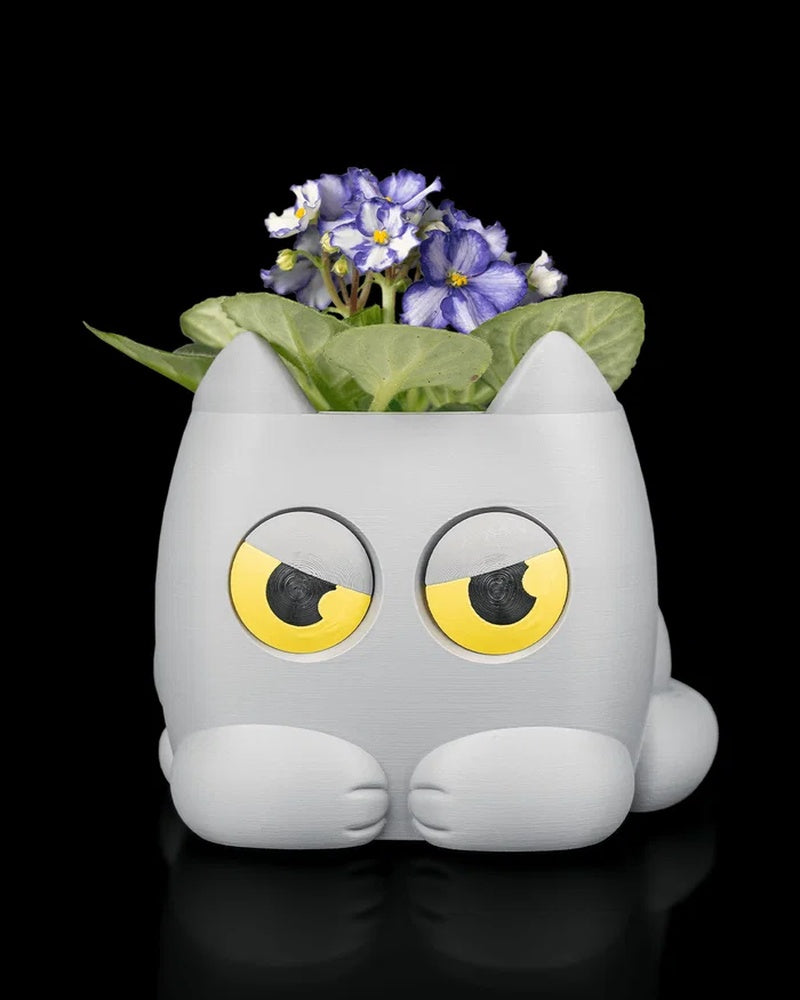 Gray cat-shaped planter holding a small flowering plant on a black background