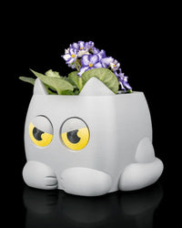 Angled view of a gray cat-shaped planter with flowers and green leaves inside