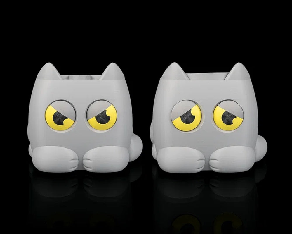 Two gray cat-shaped planters with yellow-and-black eyes side by side