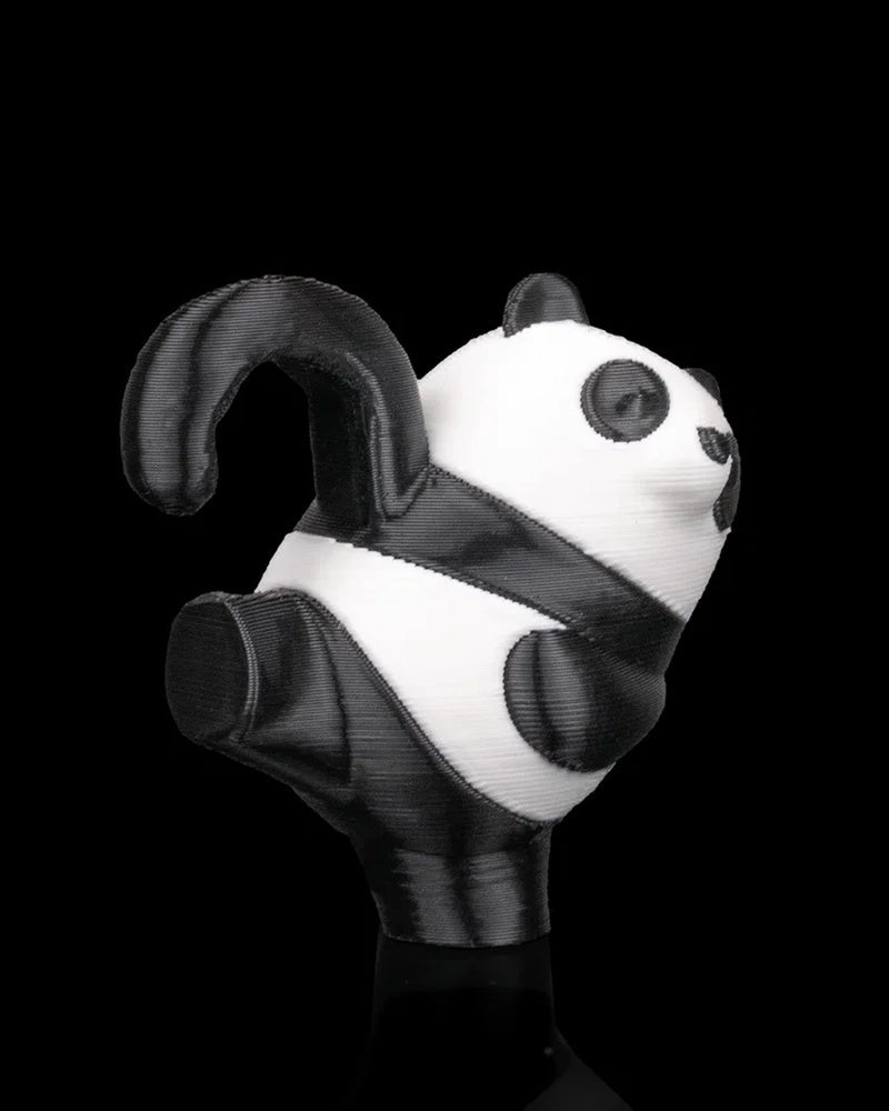 Side view of a black and white panda figurine with raised curved tail