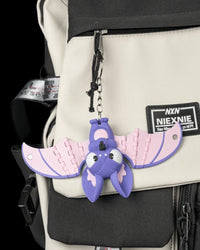 Purple and pink bat hanging from a ring and chain on a backpack