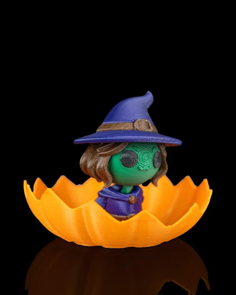 Side view of a small witch character in a blue hat inside a jagged orange pumpkin shell