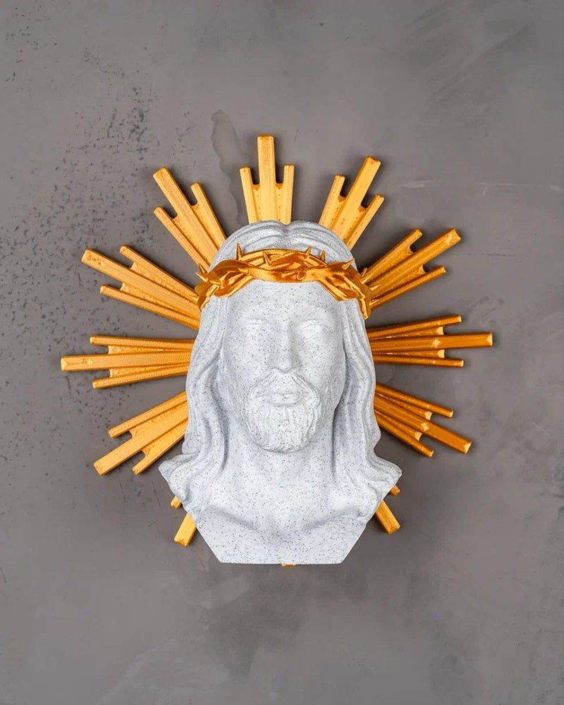 Front view of a white Christ bust with a gold crown of thorns and sunburst halo on a gray surface