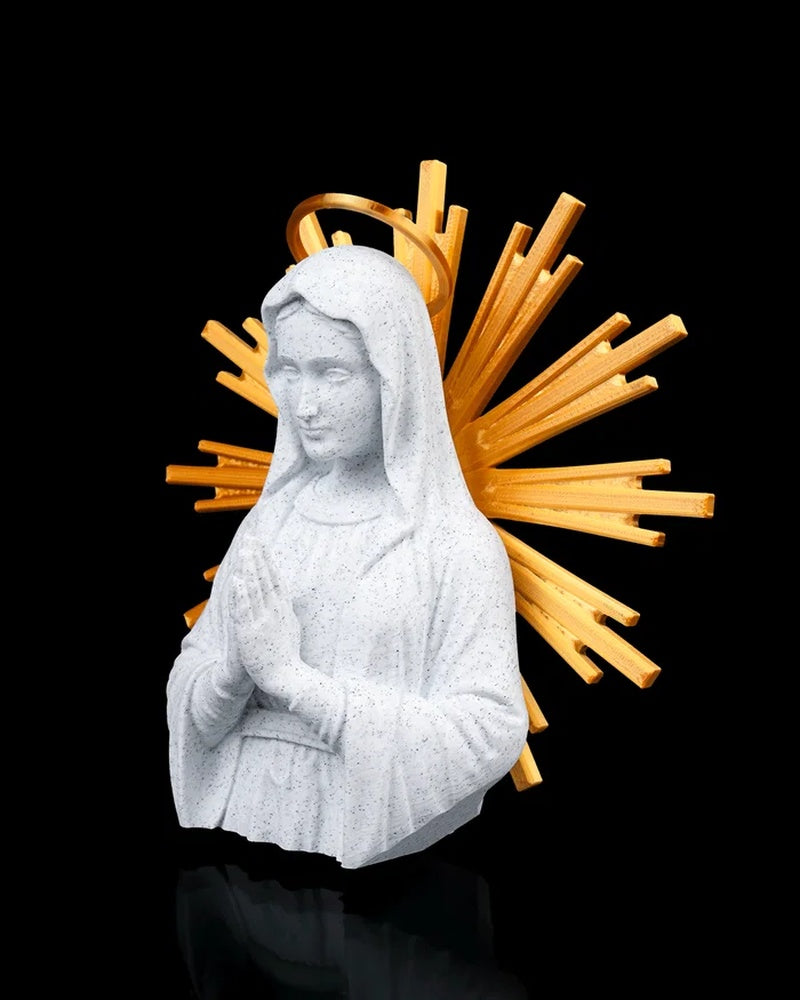 Angled front view of a Mary figurine with hands in prayer and gold-toned rays behind her on a black background