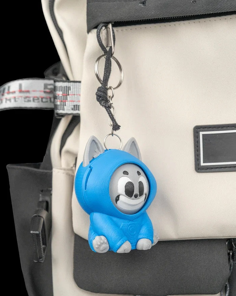 Blue hooded cat toy hanging from a metal ring and chain on a backpack