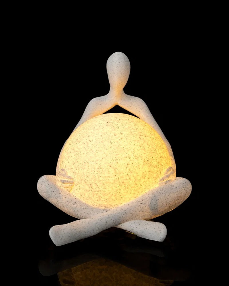 Abstract seated figure holding a warm glowing orb against a black background