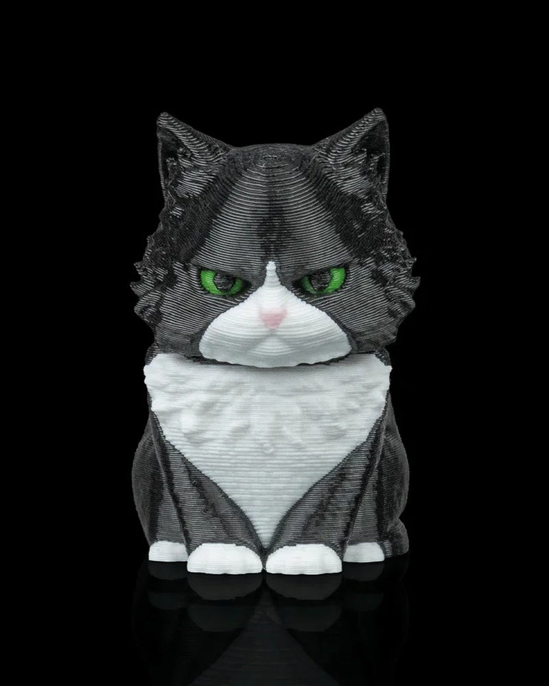 Black and white cat figurine with green eyes and a white chest on a black background