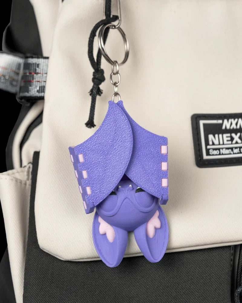 Purple bat figure hanging upside down with folded wings on a bag