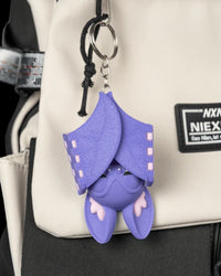 Purple bat figure hanging upside down with folded wings on a bag