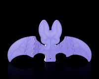 Back view of a purple bat figure with outstretched wings on a black background