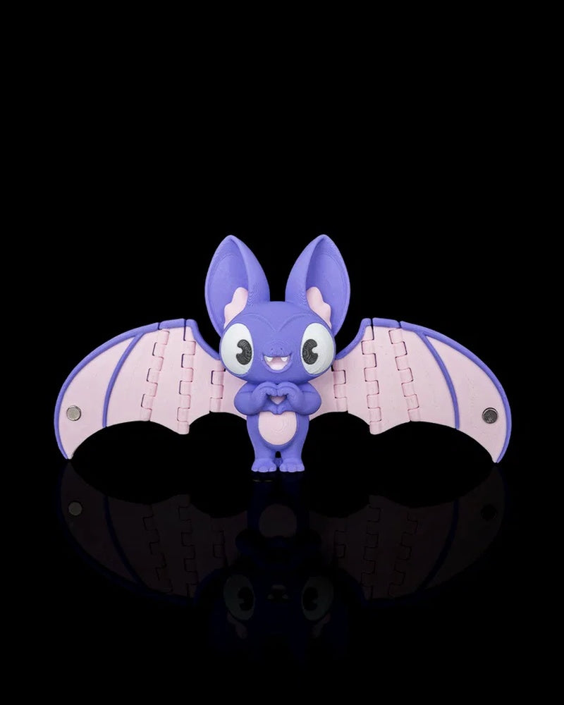 Purple and pink bat figurine with wide open wings on a black background