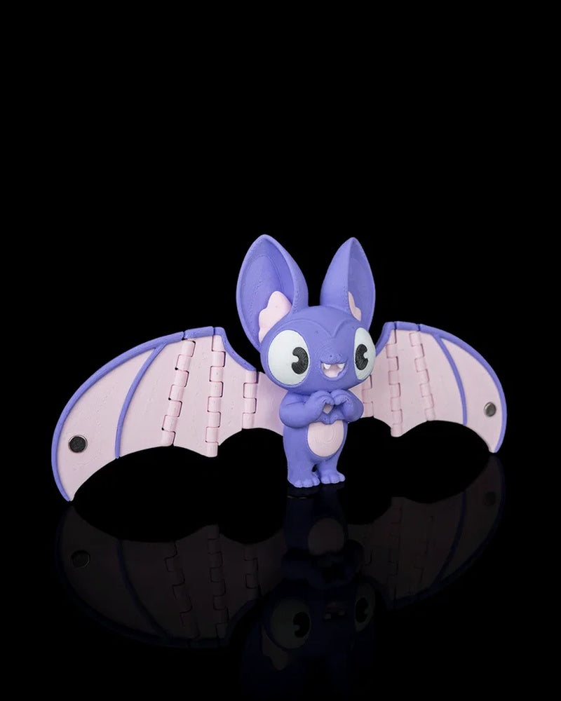 Purple and pink bat figurine viewed from an angle with wings spread