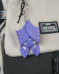Purple bat charm hanging from a metal ring and chain on a bag