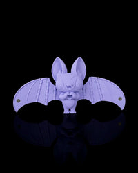 Purple bat figurine with open wings on a black background