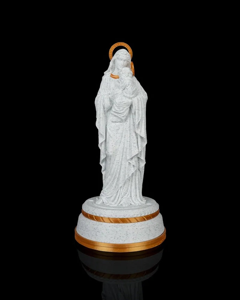 Mary holding Jesus statue on a round base against a black background with gold halo accents visible