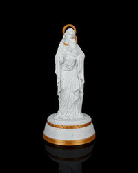 Mary holding Jesus statue on a round base against a black background with gold halo accents visible