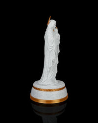 Side view of a Mary holding Jesus statue on a round base against a black background