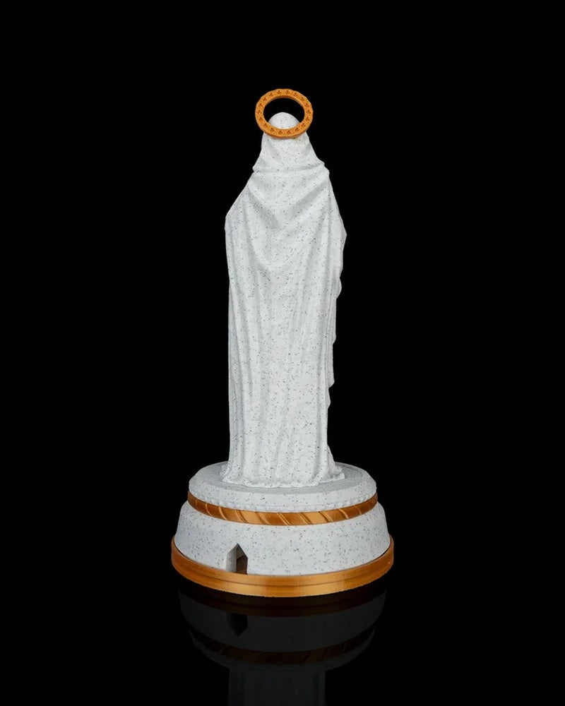 Rear view of a robed statue on a round base with a gold halo ring against a black background