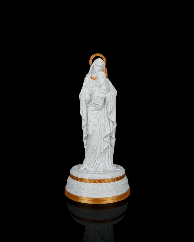 Mary holding Jesus statue on a round base against a black background with gold halo and trim accents