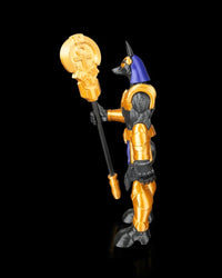 Side view of a black, gold, and blue jackal-headed figurine holding a staff.