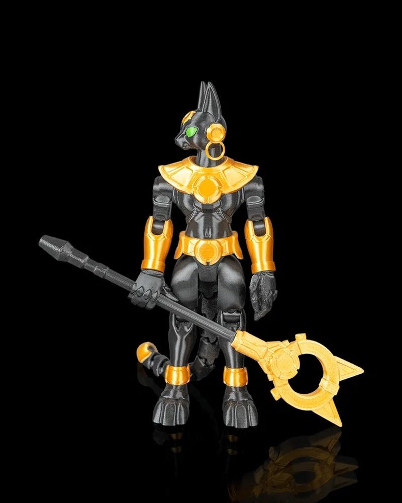 Front view of a black-and-gold cat-headed figurine with green eyes holding a long staff on a black background.